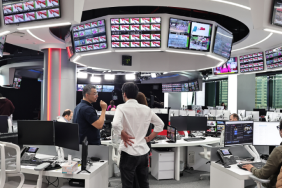 Modern newsroom with multiple monitors and staff working on editorial tasks.