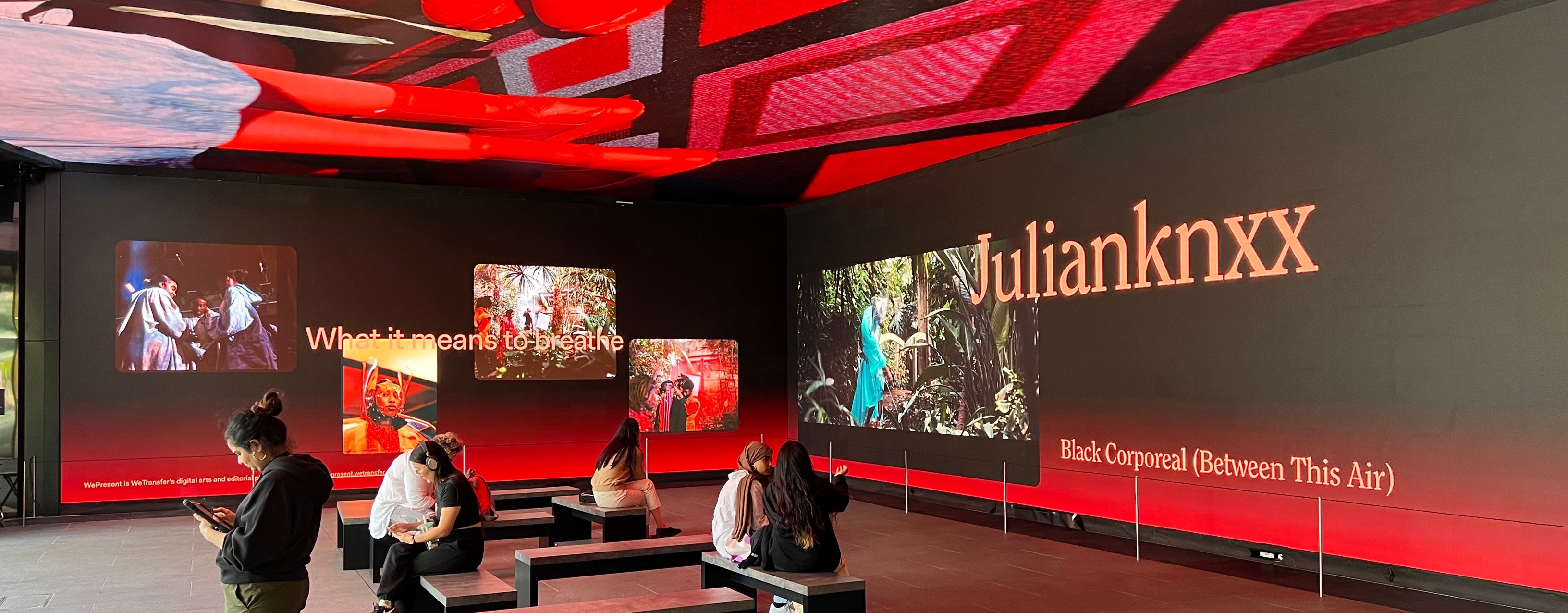 Visitors viewing an immersive video installation in a modern exhibition space.