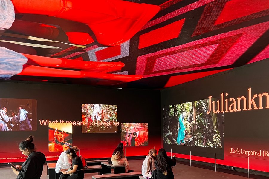 Besucher:innen betrachten eine immersive Videoinstallation in einem modernen Ausstellungsraum.