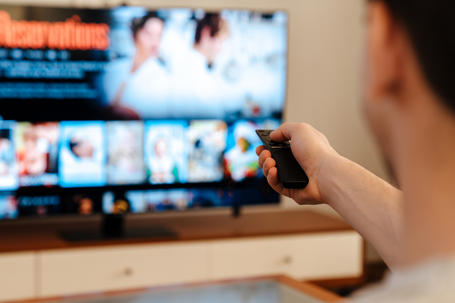 Person schaut mit Fernbedienung Fernsehen.