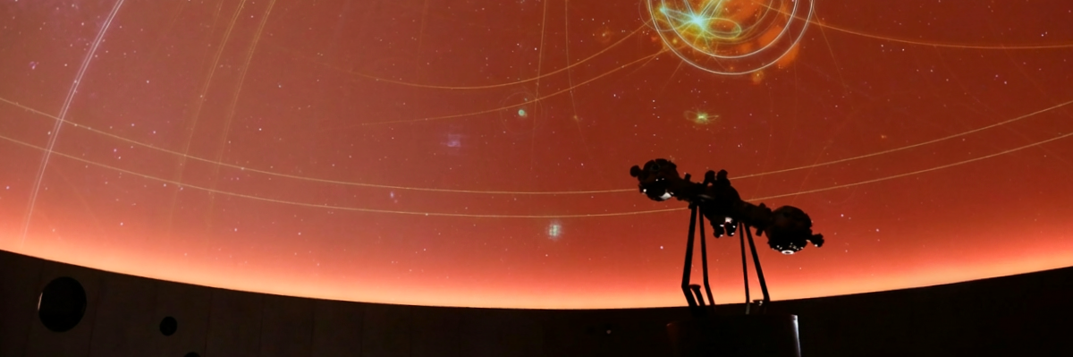 Planetarium dome showing a projected starry sky with the silhouette of a telescope.