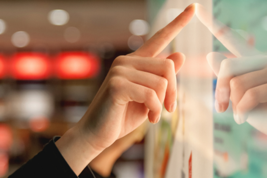 Woman using an interactive touchscreen in a modern retail environment.