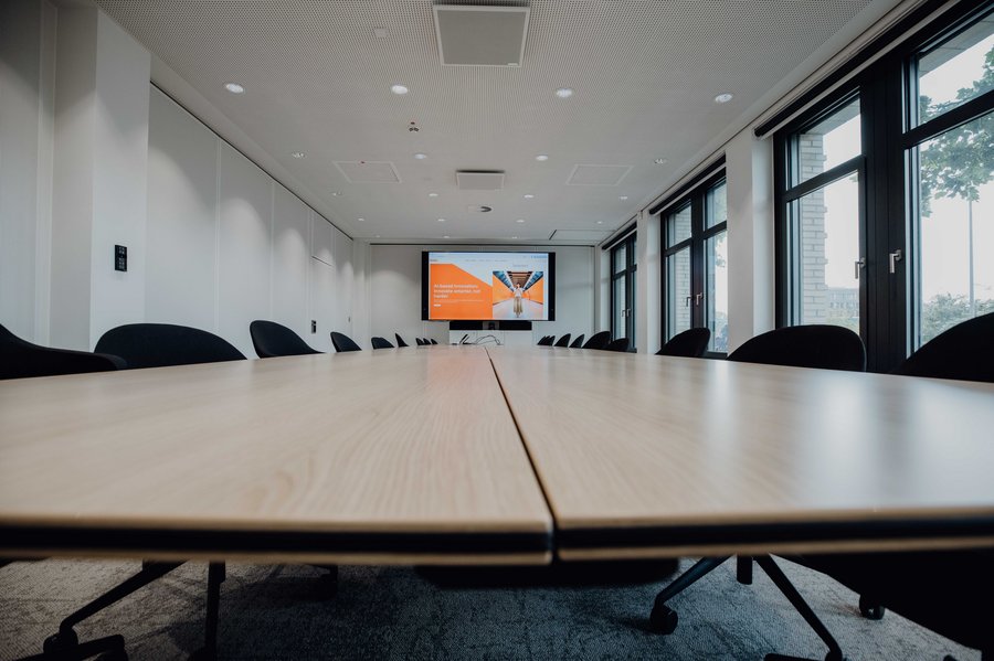 Close Up of modern conference room with a long wooden table, black chairs, and a large screen for presentations.