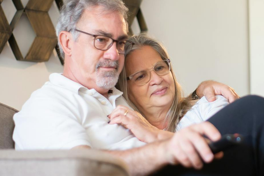 Elderly couple watching TV together.