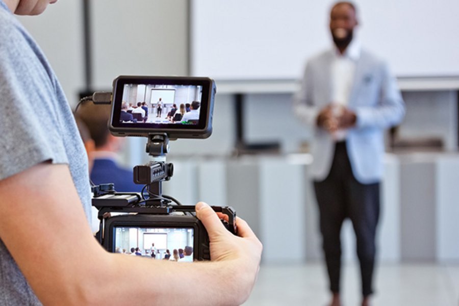 Person filming a speaker at an event.