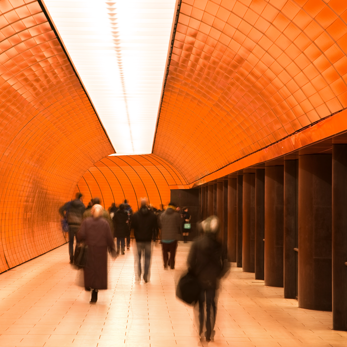 A vibrant orange tunnel with people walking through.