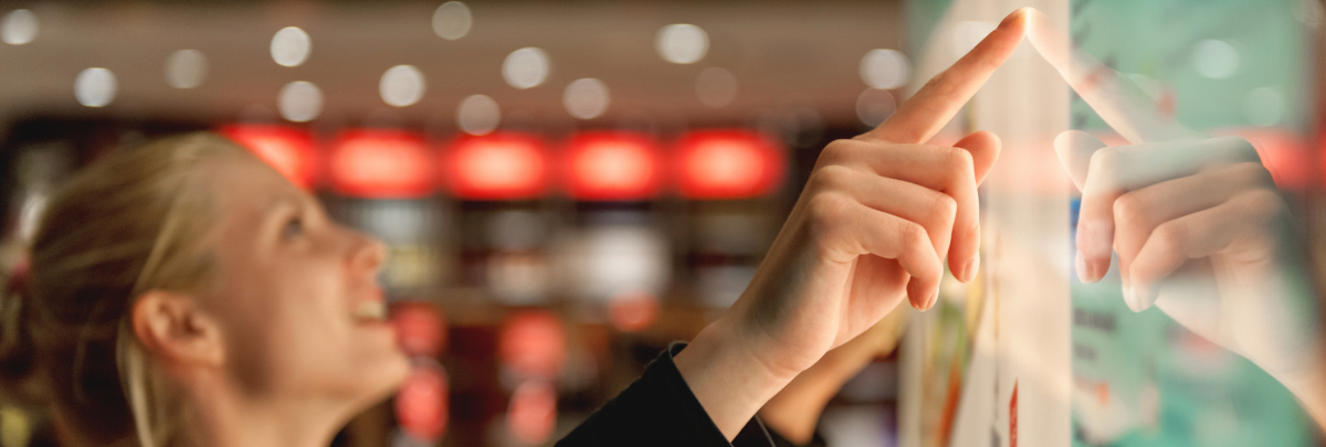 Frau bedient einen interaktiven Touchscreen in einer modernen Einzelhandelsumgebung.